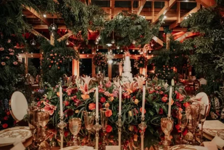 Montaje de boda con mesas decoradas con cristalería fina y flores rojas