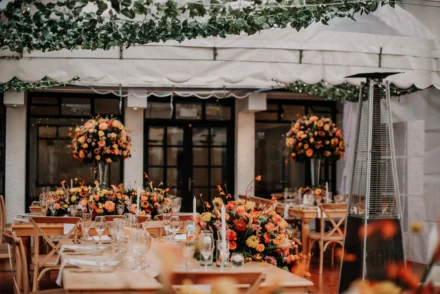 Decoración de boda en tonos naranja y dorado con mesas elegantes.