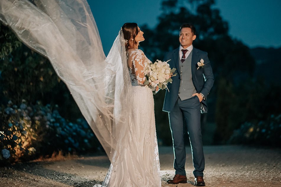 una pareja durante su matrimonio campestre, con el velo de la novia creando un efecto mágico bajo las luces