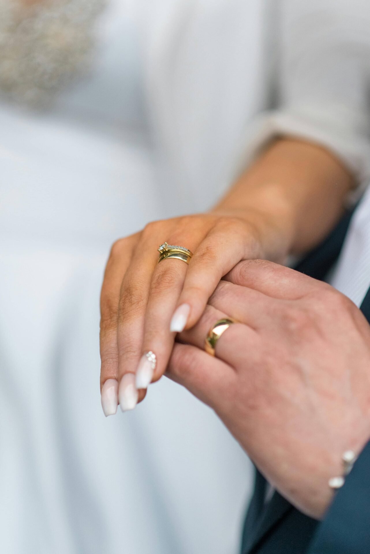 Manos-de-novios-con-anillos-de-boda. Manos de los novios mostrando sus anillos de boda, con una manicura francesa clásica para ella.