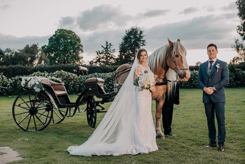 Novios junto a un carruaje en su boda destino en Colombia rodeada de naturaleza