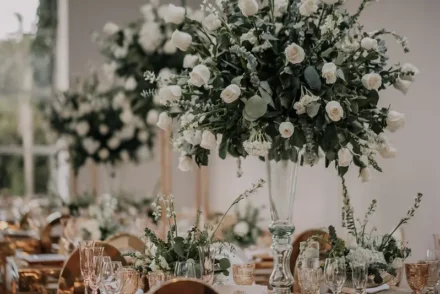 Mesa de boda con decoración floral blanca y candelabros dorados.