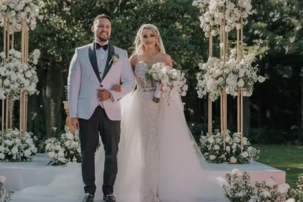 Pareja de recién casados posando con sonrisas en un jardín.