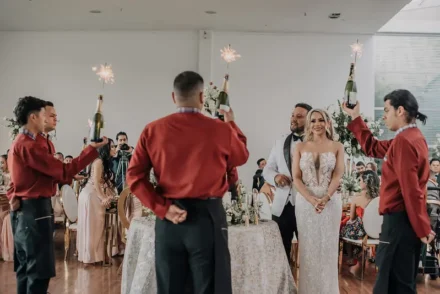 Pareja de novios brindando en una recepción de boda iluminada.