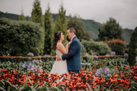 Pareja de novios rodeados de flores en un jardín romántico