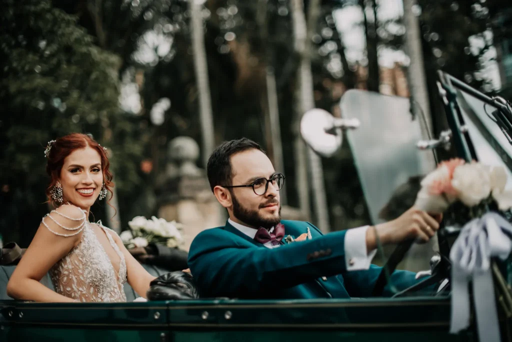 Novia besando a su esposo en un carro clásico de bodas