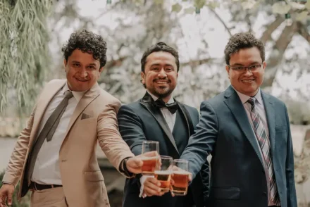 Grupo de amigos brindando con whisky en una boda elegante