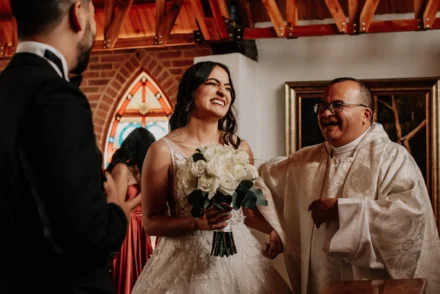 novia levantando su ramo de flores mientras sale de la iglesia.