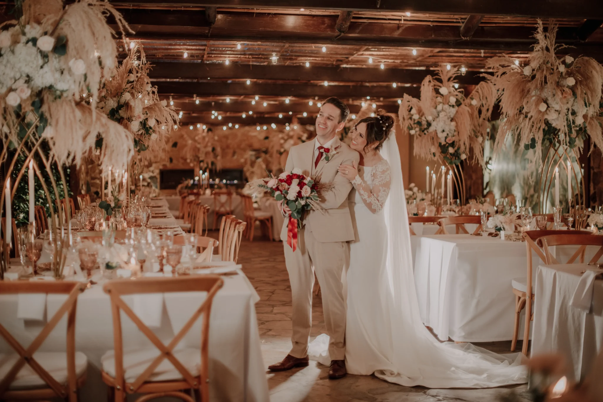 Pareja de novios posando para sus fotos en salón de recepciones decorado.