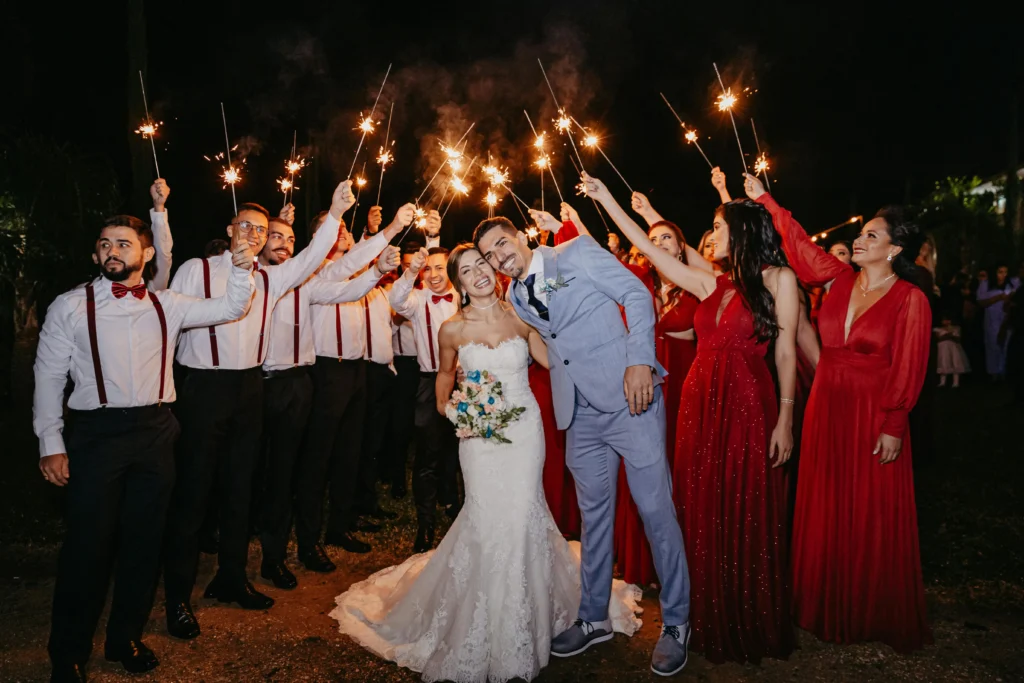 Novios besándose bajo un arco de luces de bengala sostenidas por invitados en su celebración de bodas en Santa Marta.
