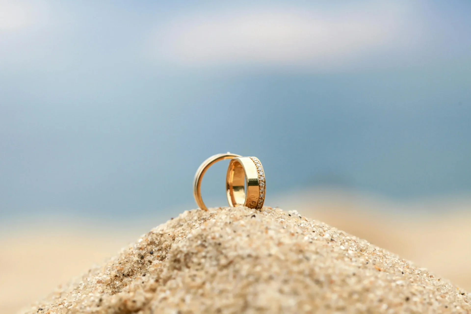 Par de anillos de matrimonio sobre la arena con el mar de fondo, símbolo de amor eterno en bodas en San Andrés.