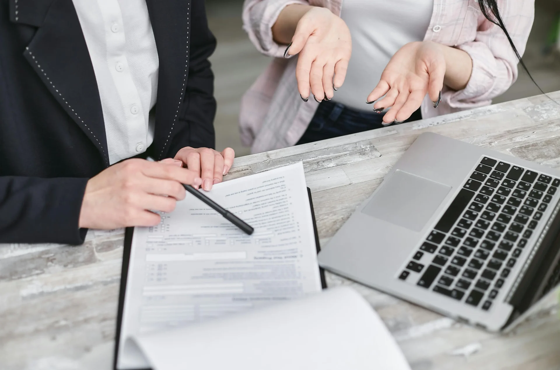 Personas revisando documentos o firmando un contrato, representando la planificación y los requisitos legales de un matrimonio