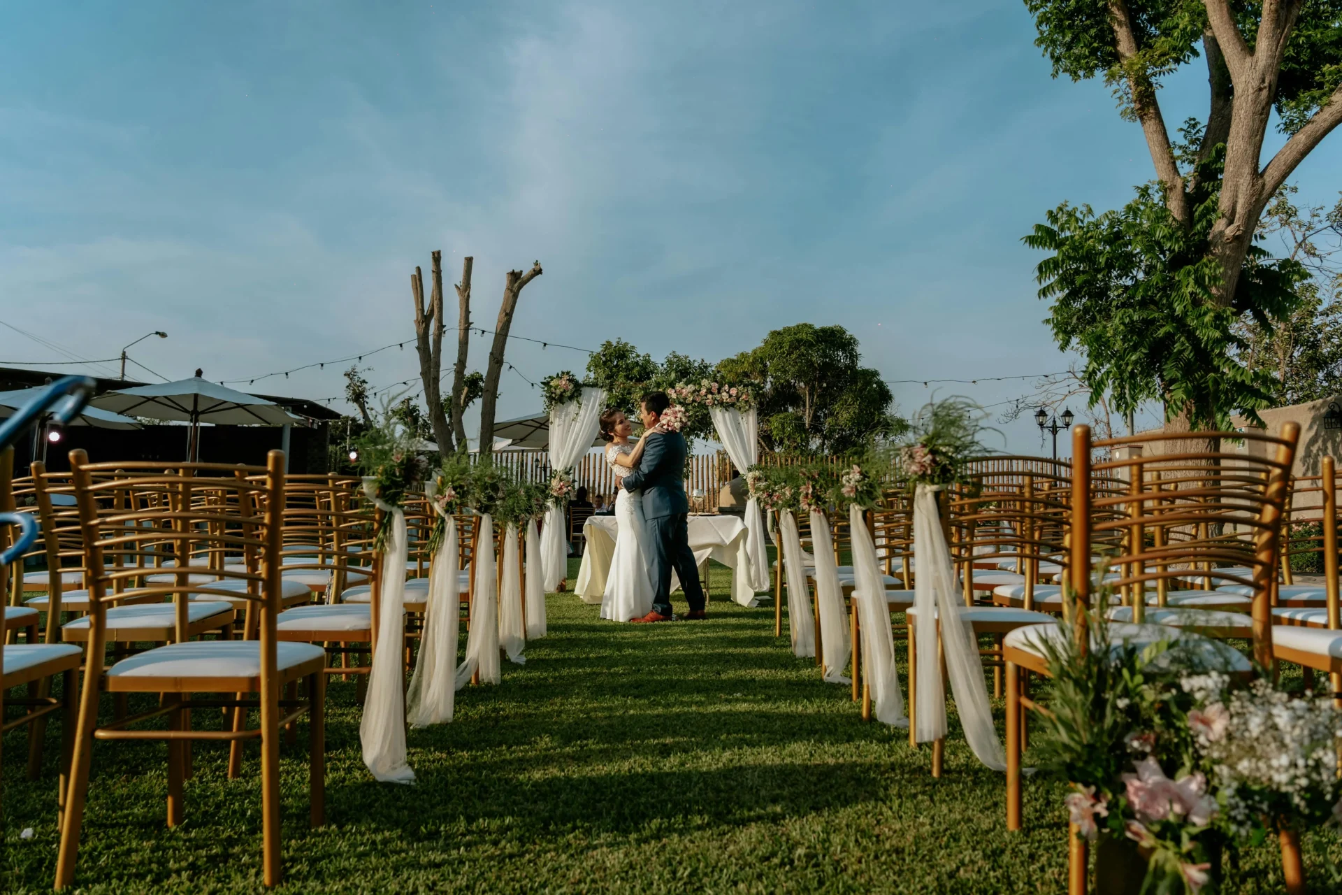 Montaje de ceremonia para una boda espiritual al aire libre en Colombia, mostrando el pasillo con sillas doradas decoradas y una pareja en el altar al fondo
