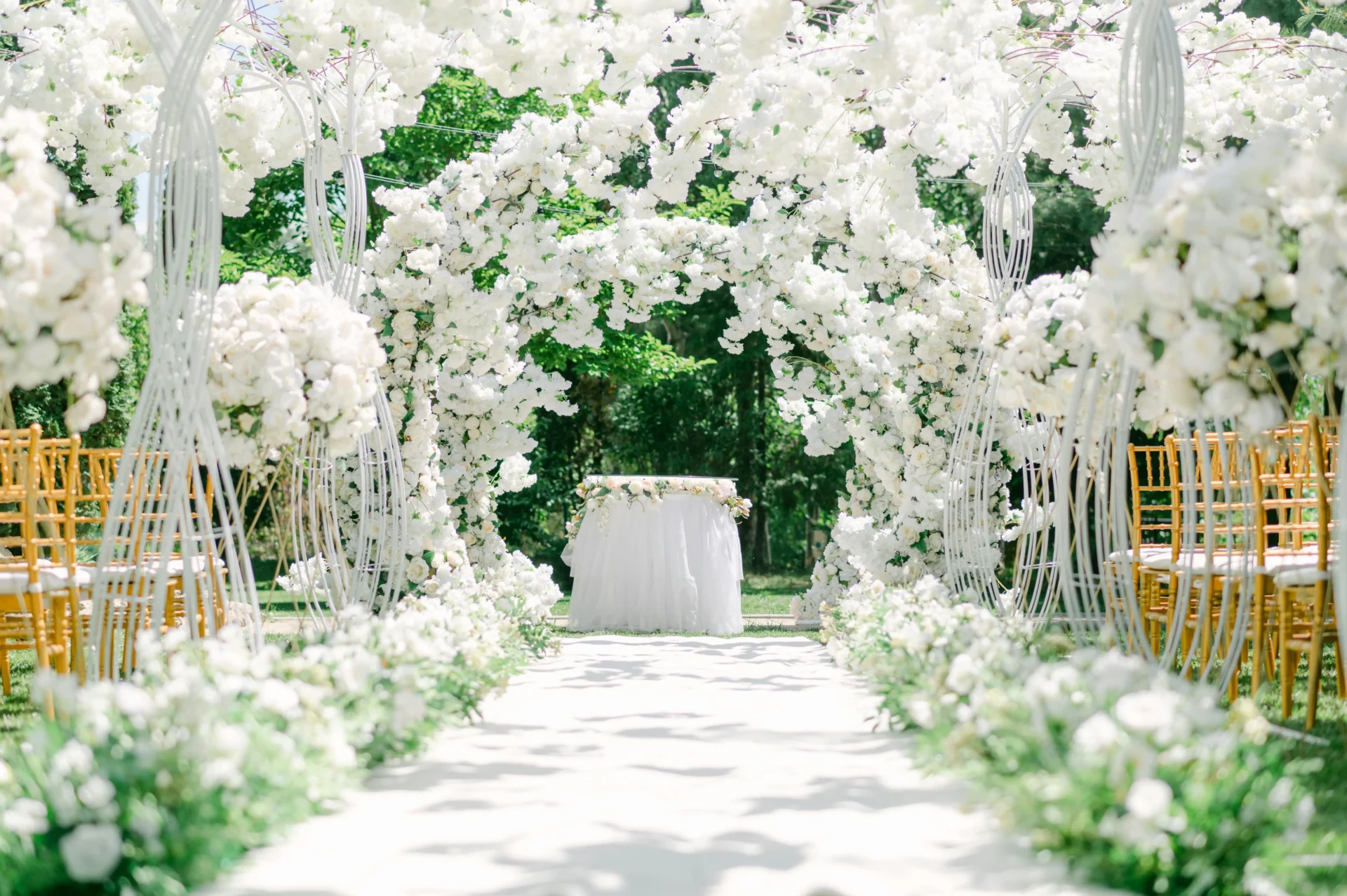 Pasillo de ceremonia para bodas en Guatavita, con un camino blanco y arcos completamente cubiertos de flores blancas que llevan a un altar.