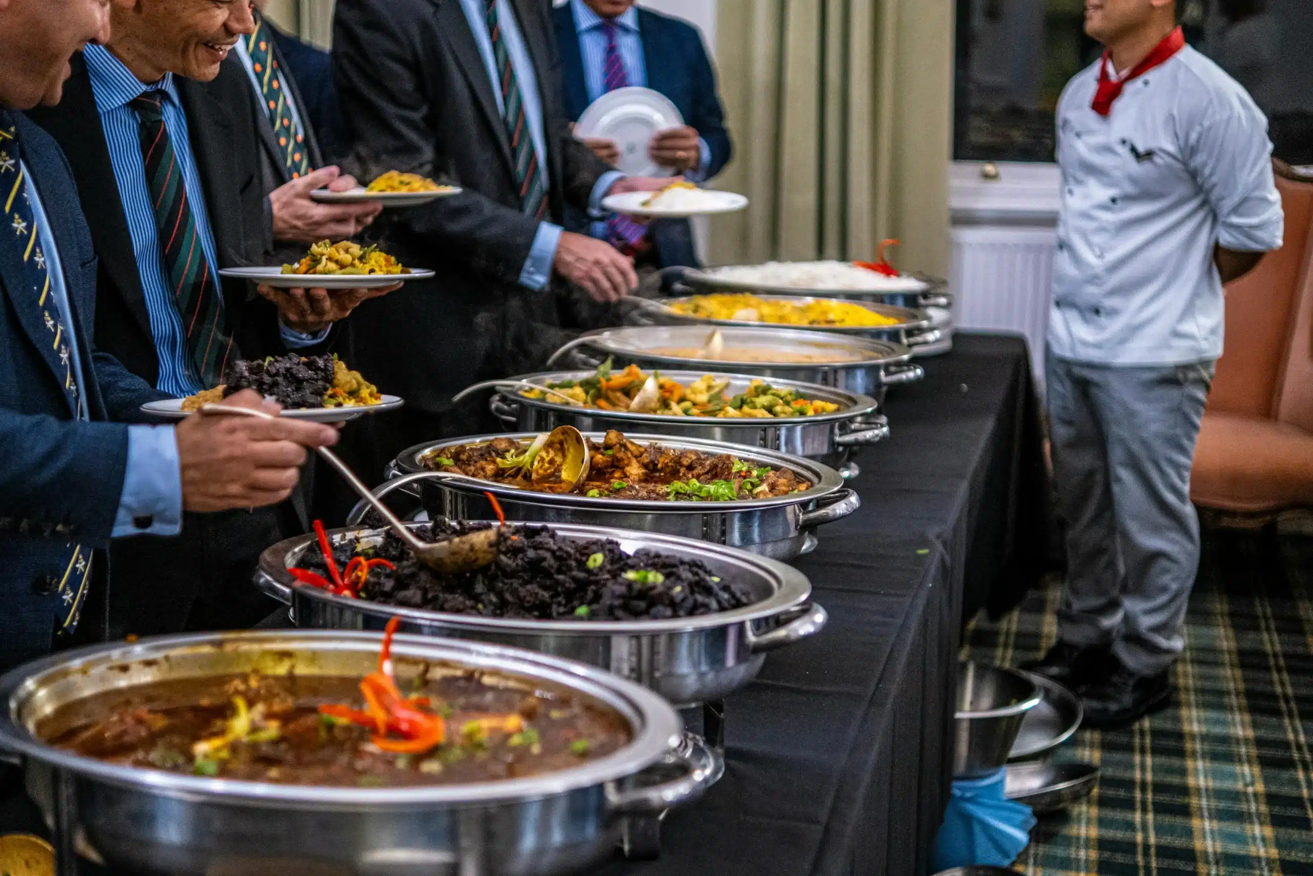 Servicio de catering tipo buffet para eventos empresariales en Bogotá, con invitados disfrutando de una variedad de platos. 