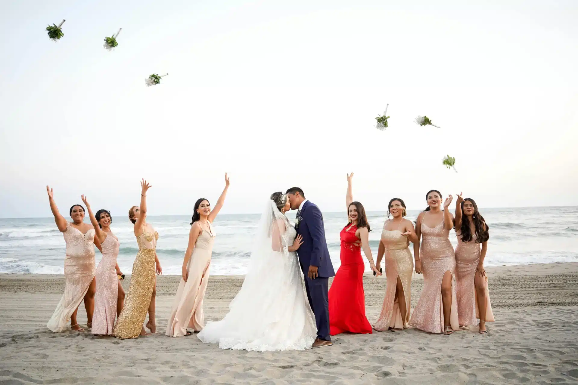 Matrimonio en la playa con novios y damas de honor celebrando una boda tropical junto al mar