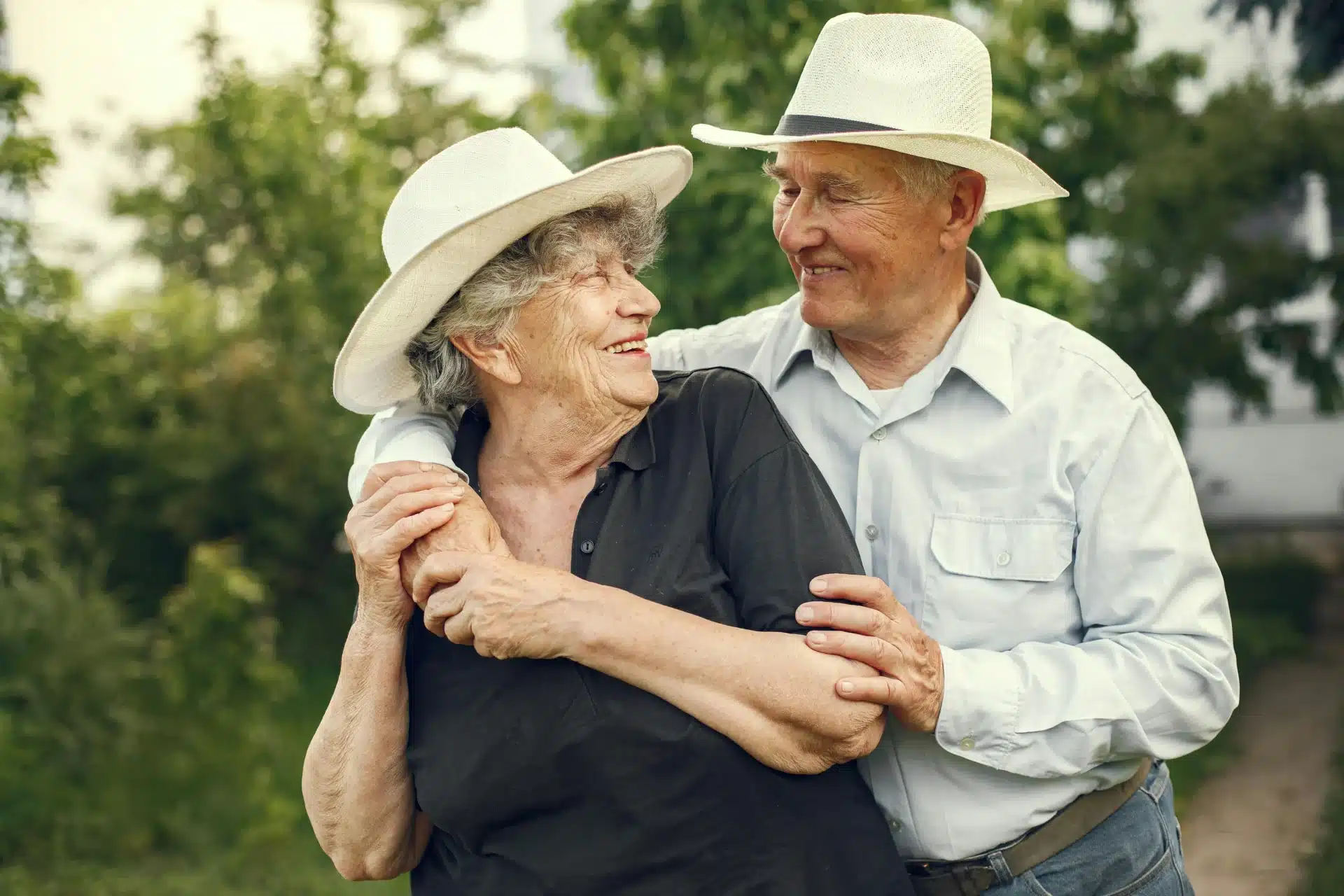Pareja de adultos mayores sonriendo y abrazados en un jardín, ideal para ilustrar la complicidad en una boda de diamante.