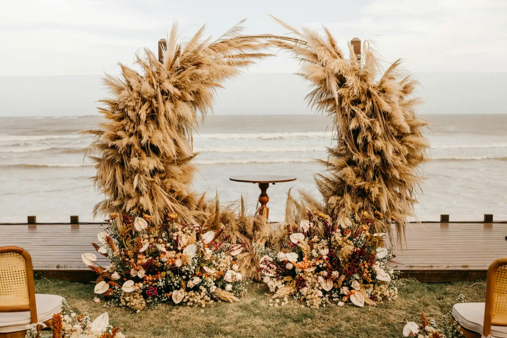 Matrimonio en la playa con altar boho de flores secas y decoración elegante frente al océano