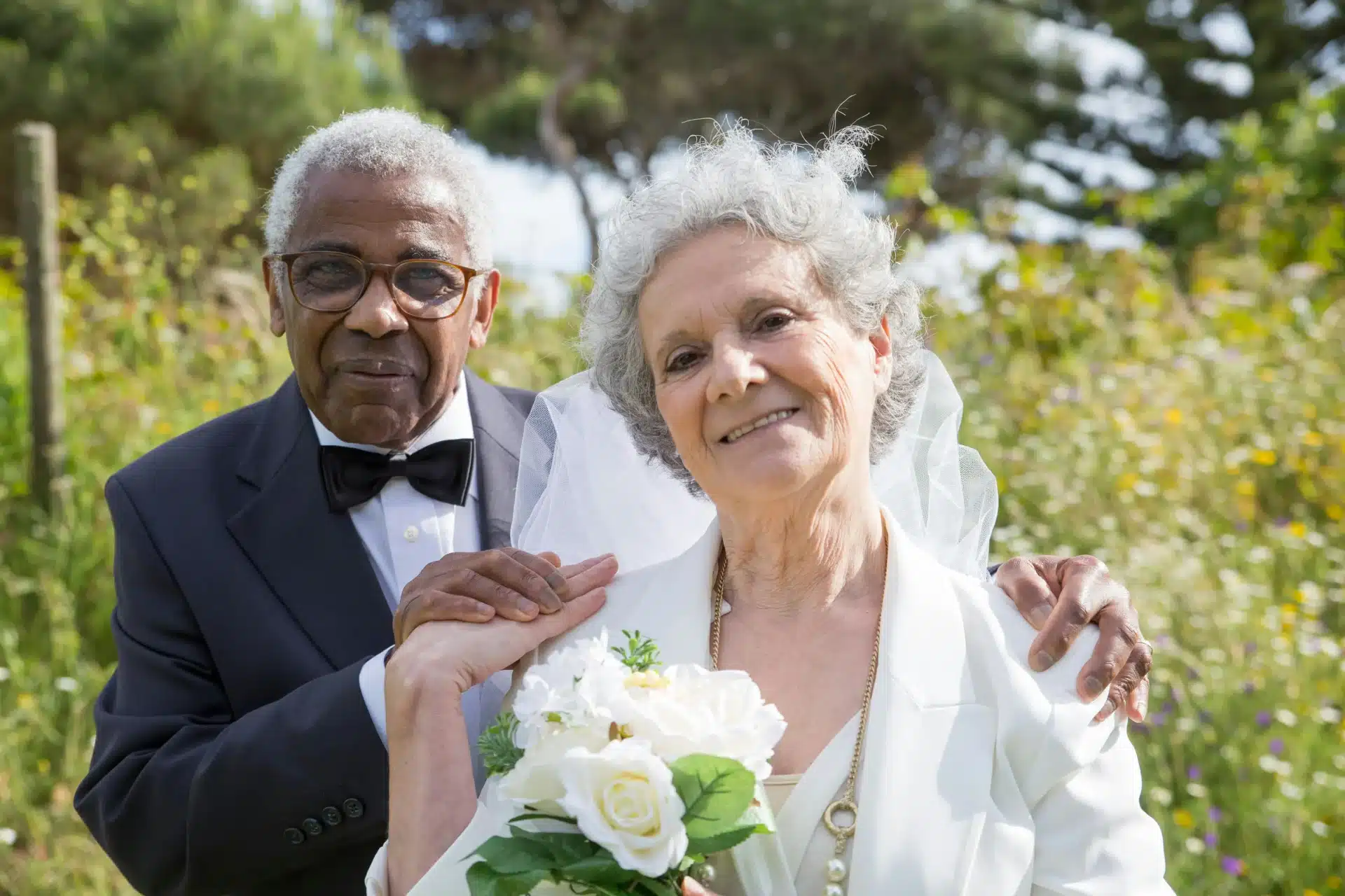 Celebración de bodas de diamante en Bogotá con esposos mayores elegantes luciendo un ramo de rosas blancas.
