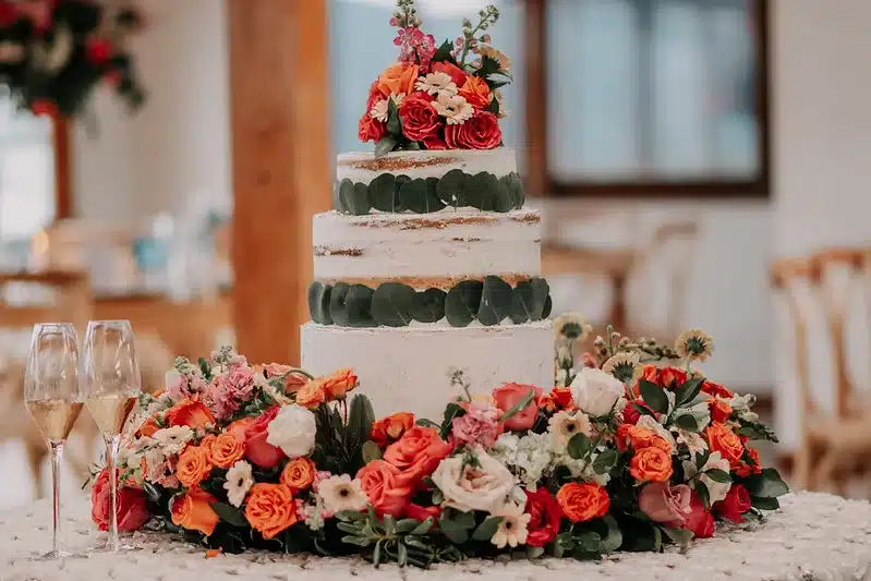 Torta de matrimonio de varios pisos decorada con flores coloridas como protagonista de una recepción de boda.