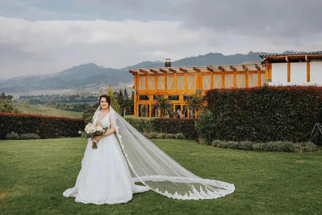 Una novia sonriente con un vestido blanco y un velo largo de tul