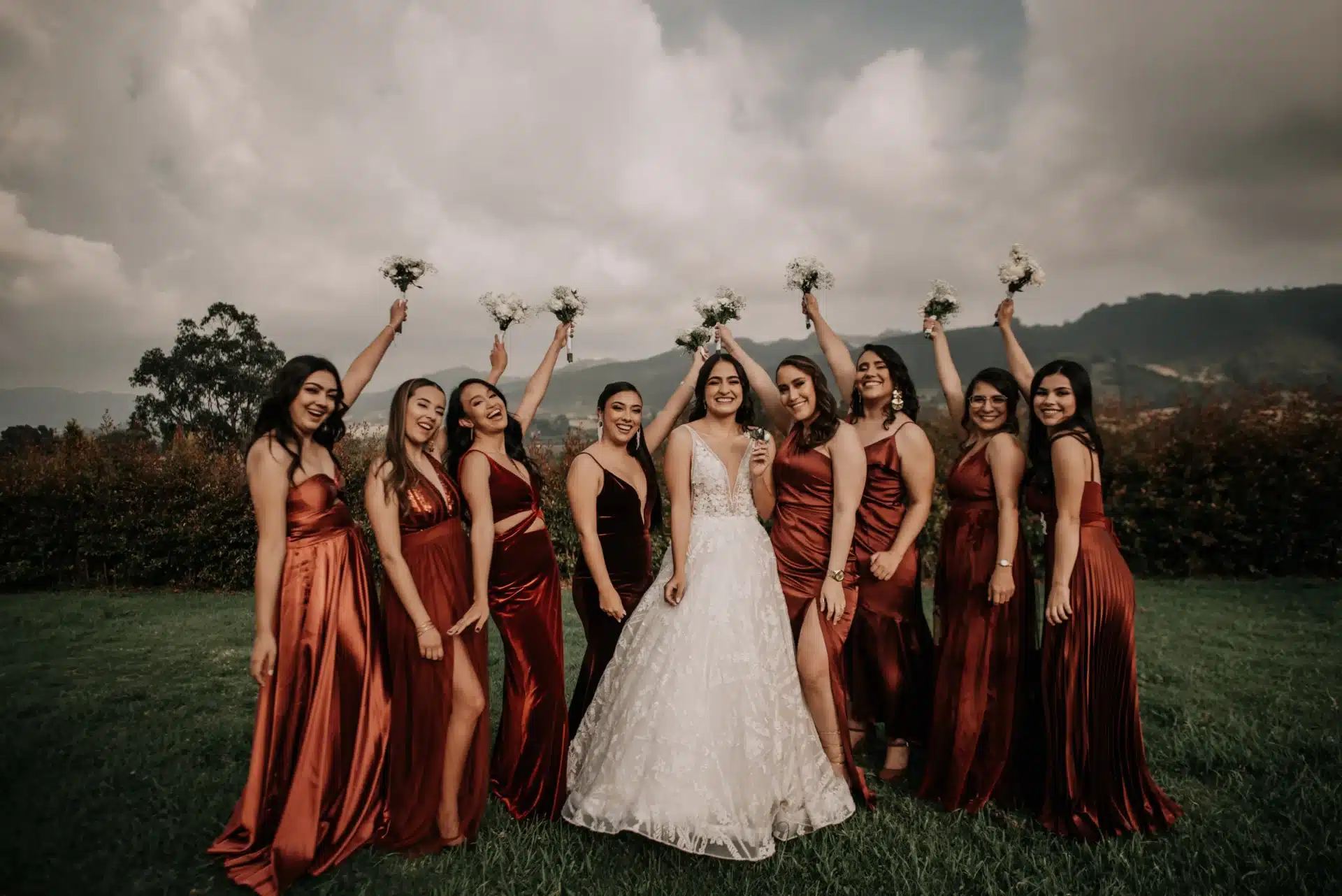 Acompañantes de la novia y damas de honor reunidas alrededor de la novia durante una boda al aire libre con paisaje natural.