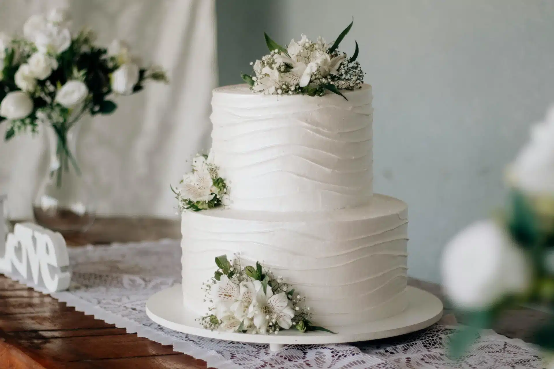Torta de matrimonio blanca de dos pisos con decoración floral elegante, ideal para bodas románticas y celebraciones íntimas.