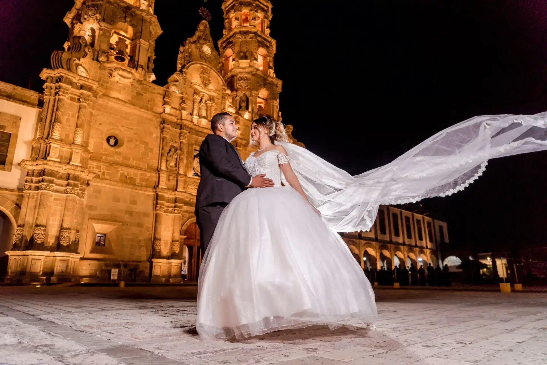 Novios vestidos de boda frente a una capilla en Cartagena durante su celebración matrimonial.